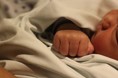 Low section of baby lying on bed