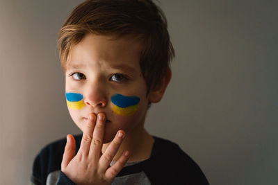 Portrait of a ukrainian boy with a face painted with the colors of the ukrainian flag.