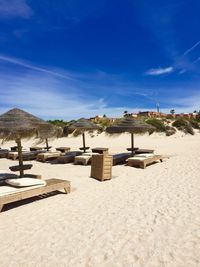 Chairs on beach against blue sky