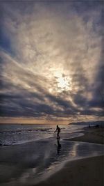Man on beach against dramatic sky