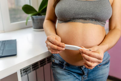 Midsection of woman holding thermometer
