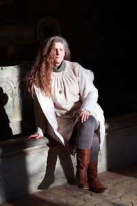 Full length portrait of senior man sitting against wall