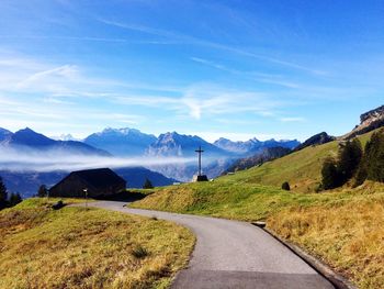 Road amidst landscape against blue sky