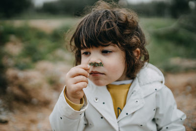 Close-up of girl smelling plant outdoors