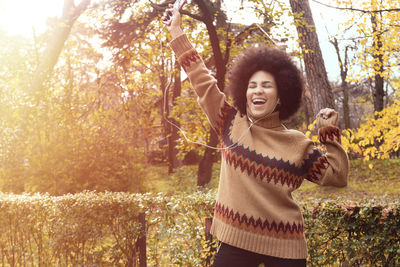 Portrait of smiling young woman standing by tree