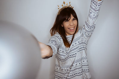 Portrait of young woman standing against wall