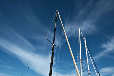 Low angle view of masts against blue sky