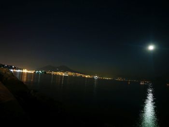 Illuminated lake against clear sky at night