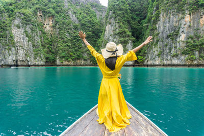 Rear view of woman with yellow umbrella in water