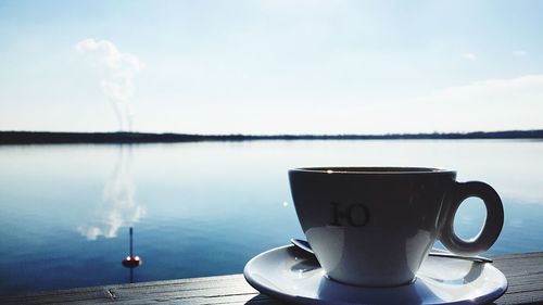 Coffee cup on table against sky