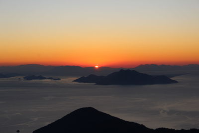 Scenic view of silhouette mountains against romantic sky at sunset
