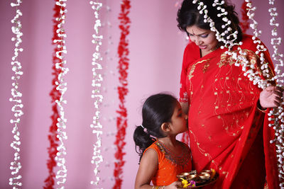 Rear view of mother and daughter standing against red wall