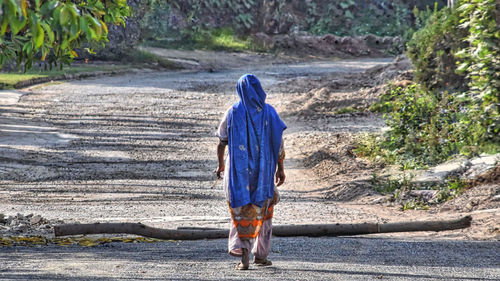 Rear view of woman walking on road