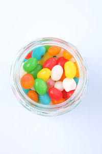 Multi colored candies in jar against white background