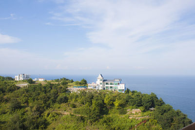 Buildings by sea against sky