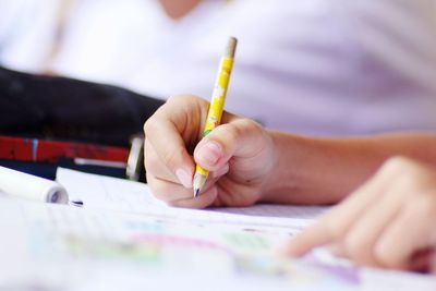 Cropped of hand of child writing on book on desk