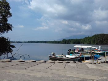 Boats moored at lakeshore against sky