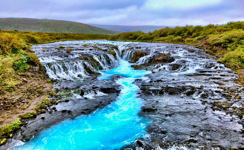 Scenic view of waterfall against sky