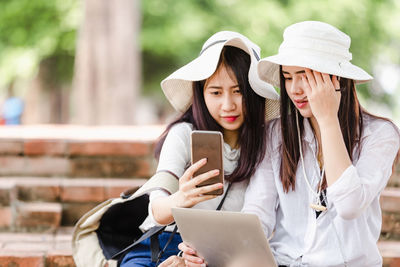 Friends looking away while using mobile phone