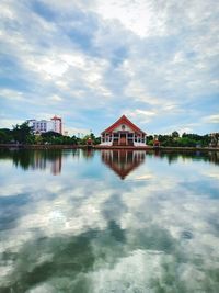 Houses by lake and buildings against sky