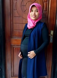 Portrait of young woman standing against wall
