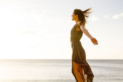 Young woman standing on beach against clear sky