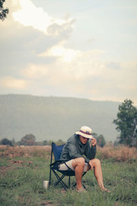 Full length of man sitting on land against sky