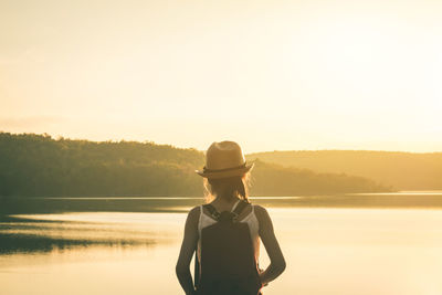 Man standing by lake against clear sky during sunset