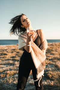 Young woman with a wine glass in a field at sunset