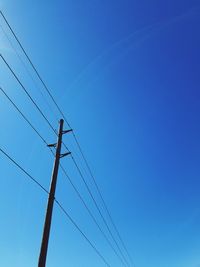 Low angle view of power lines against clear blue sky