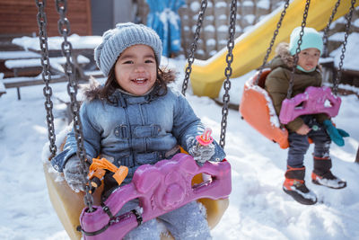 Portrait of smiling boy swinging at playground