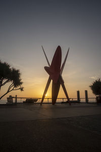 Silhouette built structure on beach against sky during sunset