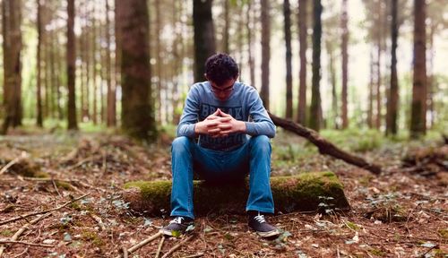 Full length of man sitting on tree trunk
