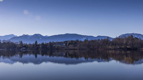 Scenic view of lake and mountains against clear blue sky