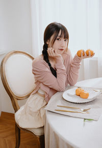 Portrait of young woman sitting on sofa at home