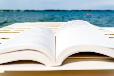 Close-up of open book on table against sea