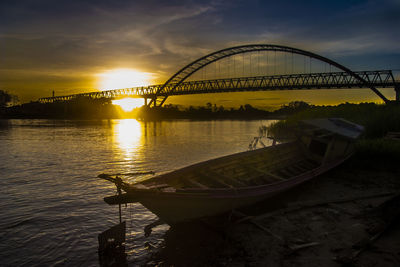 Bridge over river against sky during sunset