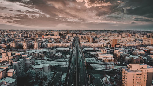 High angle view of city buildings against cloudy sky
