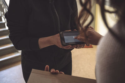 Midsection of customer signing on phone during home delivery