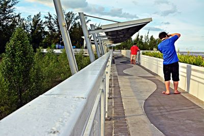 Rear view of a woman standing on railing