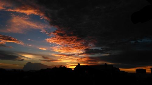 Silhouette trees against dramatic sky during sunset