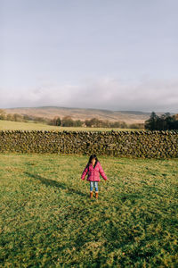 Rear view of woman standing on field against sky