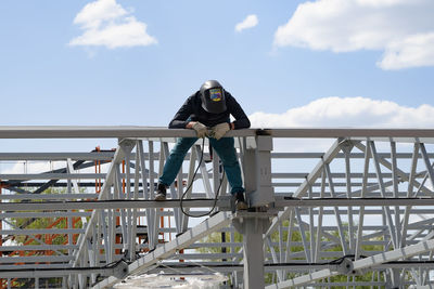 Rear view of woman standing on bridge against sky