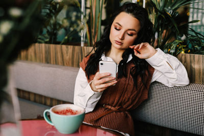 Young woman using phone while sitting at table