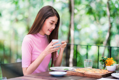 Woman holding coffee cup sitting at outdoor cafe