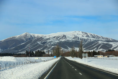 Road leading towards snowcapped mountains against sky