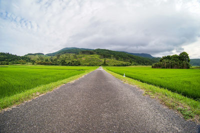 Road amidst green landscape against sky