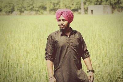 Young man wearing pink turban while standing at farm