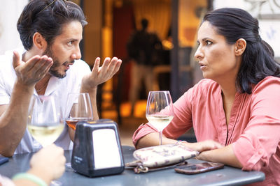 Friends looking away while sitting on table in restaurant