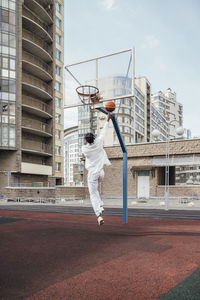 Young man throwing basketball at sports court